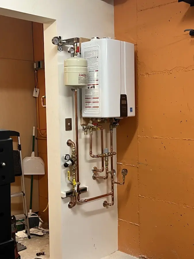 Plumbing technician inspecting water heater connections in St. Joseph